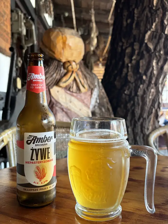 Butelka piwa i pełny kufel na drewnianym stole w pubie