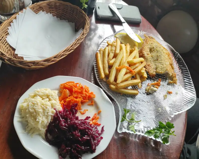 Smażona ryba z frytkami, surówkami i chlebem na stole w pubie